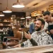 A client sitting in a barber chair smiling and discussing his haircut preferences with a professional barber.