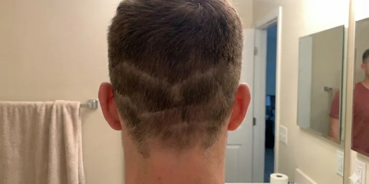 Rear view of a person's head showing a botched DIY haircut with multiple uneven, horizontal fade lines and patchy lengths in a home bathroom setting.