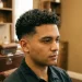 "Man with low taper fade curly hair and natural curls on top."