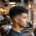 Side profile of a stylish man with a neat low fade curly hair haircut and voluminous curls in a modern barbershop